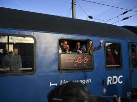 Des passagers saluent les journalistes depuis un wagon du premier train de nuit de la ligne Paris-Berlin gérée par la compagnie néerlando-belge European Sleeper, au départ de la Gare du Nord à Paris, le 26 mars 2026 © JULIEN DE ROSA / AFP